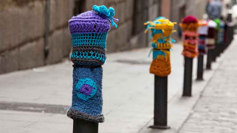 Bolards covered with colorful crochet knits in a street in Madrid.